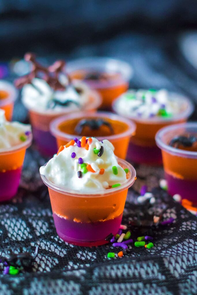 Halloween Jello Shots - Orange and grape flavors with whipped cream, colorful sprinkles and even a chocolate cobweb.